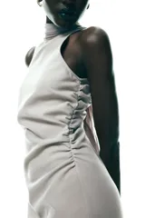 Vestido midi color gris topo, de cuello halter con lazada combinada a tono. Bajo con abertura en espalda. Cierre en espalda con cremallera, abertura y botón.