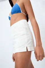 Short de jean color beige, con calce medio, bolsillos funcionales y tajos pequeños en el ruedo.