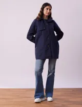 Gabardina impermeable color beige, marca Weatherproof, con abertura central con botones, bolsillos delanteros y capucha desmontable.