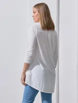Camisola blanca de manga tres cuartos, marca Rio & Rian. Cuello con solapa y abertura central con botones. Manga con detalle fruncido.