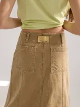 Falda midi color beige, de corte evasé, con bolsillos delanteros y ruedo desflecado.