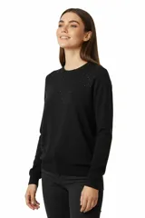 Buzo de punto color negro con cuello redondo y pequeños apliques brillantes en la parte superior.