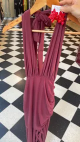 Vestido largo color uva confeccionado en microtul, con escote profundo en V tipo halter y falda con diseño de frunces y transparencias.