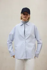 Camisa de algodón a rayas verticales finas celestes y blancas, con cuello clásico y corte holgado.