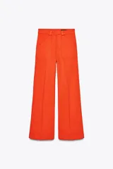 Pantalón de tiro alto color naranja, corte wide leg y largo hasta el tobillo. Tiene bolsillos de parche delanteros y cierre frontal con cremallera y botón.
