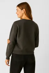 Buzo negro de algodón con cuello redondo y mangas largas. Estampado frontal de mariposa en blanco y negro con texto "The Butterfly" y tachas plateadas en los hombros.