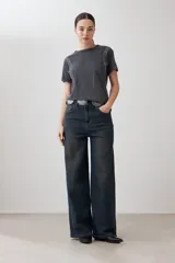 Remera gris oscuro con cuello redondo y tachas plateadas en los hombros.