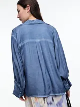 Camisa gris de manga larga confeccionada en viscosa teñida en frío, con efecto gastado. De corte relajado, con bolsillo delantero y puños amplios.