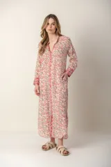 Vestido largo con estampado floral en tonos rosa y verde sobre fondo blanco. Tiene cuello con volantes, cierre frontal con botones y mangas largas con puños elásticos.