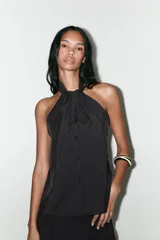 Top chaleco negro con cuello halter y cierre frontal con botones forrados.