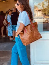 Bolso tote de cuero color marrón con asas trenzadas en marrón y rojo.