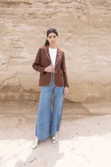 Blazer corto color chocolate de lino con solapas de muesca, cierre frontal con dos botones, bolsillos de parche y ribete en contraste color crema.