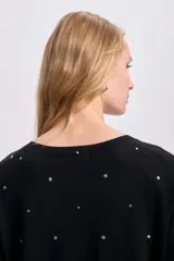 Buzo negro de punto fino con cuello redondo y tachas plateadas en forma de estrella.