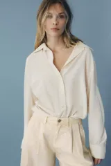 Camisa color crema de manga larga con cuello solapa y cierre frontal con botones.