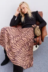 Falda midi plisada con estampado animal print de cebra en tonos beige y marrón. Tiene cintura elástica.