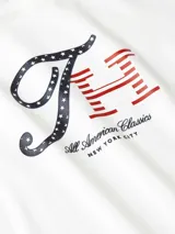 Remera blanca de algodón con logo gráfico de Tommy Hilfiger en azul y rojo.
