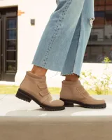 Botín corto de cuero color visón (beige/topo), con cierre de tres tiras de velcro en el empeine. Posee cuello acolchado de gamuza y suela de goma negra con relieve tractor.