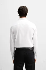 Camisa blanca de corte slim fit, confeccionada en algodón, con cuello italiano, mangas largas con puños abotonados y cierre frontal con botones.
