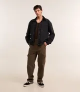 Pantalón baggy color marrón confeccionado en sarga de algodón, con cintura con trabillas, cierre tradicional y bolsillos cargo laterales.