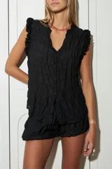 Blusa negra con textura arrugada, escote en V, mangas cortas con volados y cierre frontal con botones.