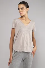 Remera color beige con escote en V, corte relajado, bordes sin rematar, detalles de costura central expuesta y dobladillo estilo camisero.