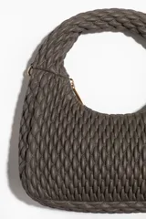 Cartera bandolera color gris topo, con asa corta superior trenzada y correa larga extraíble. Diseño guateado con cierre superior.