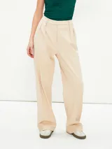 Pantalón de vestir color crudo, de corte ancho y tiro alto, con pinzas en la cintura.