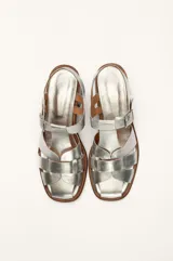 Sandalias plateadas de cuero con tiras entrecruzadas y hebilla lateral. Taco de madera de 6 cm.