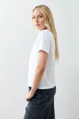 Remera blanca de algodón con cuello redondo y mangas cortas. Presenta un bordado de flores paisley en el hombro izquierdo.