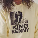 Canguro color beige con capucha y bolsillo delantero. Estampado frontal con la imagen de King Kenny y su nombre en letras negras.