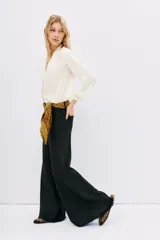 Pantalón de jean negro de corte oxford, tiro medio, con cintura y cadera ajustadas, y piernas anchas con recortes laterales.