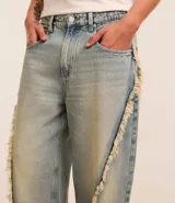 Pantalón de jean celeste de corte super baggy con cintura con trabilla, cierre tradicional, bolsillos y detalles deshilachados.
