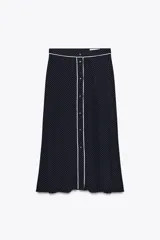 Falda midi azul marino con estampado de lunares blancos, tiro alto, bolsillos laterales ocultos, detalle de vivo blanco a contraste y cierre frontal con botones.