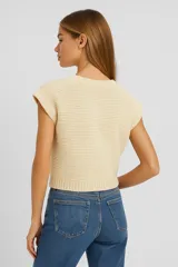 Musculosa color crema de acrílico con punto canalé, corte holgado y escote en V profundo.