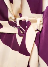 Mono largo estampado en tonos crema y morado, con diseño cruzado, cuello pico con solapa, manga larga abotonada, cinturón desmontable y forro interior.