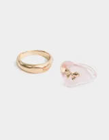 Set de dos anillos, uno dorado liso y otro rosado transparente con forma de corazón y moño dorado.
