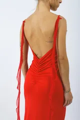 Vestido de fiesta rojo, con escote en V pronunciado, volados y flor en el centro, de corte ajustado y espalda descubierta.