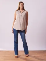 Camisa sin mangas color celeste, confeccionada en lino. Presenta cuello camisero, escote en V, abertura frontal con botones, dos bolsillos de parche en el pecho y terminación con botones en los laterales.