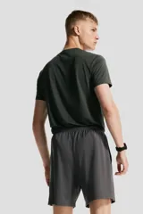 Short deportivo gris de tejido funcional de secado rápido con cintura elástica con cordón ajustable, bolsillos laterales y aberturas laterales en el bajo.