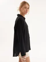 Camisa de lino negra, con corte clásico y botones en las mangas, ideal para un look elegante y versátil.