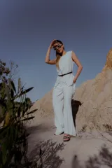 Conjunto sastrero blanco compuesto por una musculosa con forro, detalle de botones en el hombro derecho y cinto integrado, y un pantalón con elástico en la cintura y bolsillos laterales.