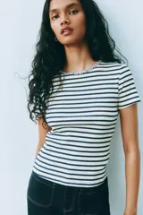 Remera de punto acanalado a rayas horizontales blancas y azul marino, con cuello redondo adornado con strass brillante. Presenta abertura de cerradura con botón en la nuca y bajo recto. Corte ajustado.