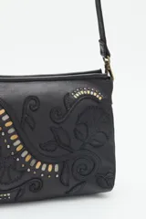 Cartera bandolera verde de cuero vacuno con bordado de flores y tachas doradas y plateadas. Tiene cierre metálico superior, forro de algodón, división interna, bolsillo y tarjetero. La correa es regulable.