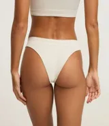 Bombacha de bikini color beige claro, confeccionada en poliamida texturizada con tecnología seamless. Presenta un corte de tiro medio/bajo con borde liso.