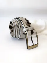 Cinto de cuero con forro de cuero, estampado animal print de vaca en blanco y negro, con hebilla metálica rectangular color bronce y broche suizo.