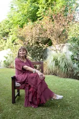 Vestido largo color cereza, con mangas amplias y escote en V. Presenta múltiples capas de tela con terminaciones deshilachadas, creando un efecto voluminoso y vaporoso.