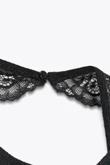 Top negro con textura, cuello halter y detalle de encaje.