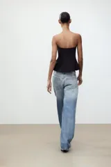 Top negro palabra de honor con peplum, confeccionado en tejido elástico con forro interior y cierre de cremallera oculta en la costura.