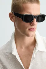 Camisa de corte relajado en color blanco, confeccionada en tejido de algodón con textura de aplicaciones. Posee cuello bowling, manga corta y cierre frontal con botones.