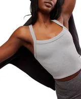 Top deportivo blanco, ajustado al cuerpo, con escote redondo en el frente y espalda cruzada. Presenta un dobladillo recortado que deja ver el abdomen.